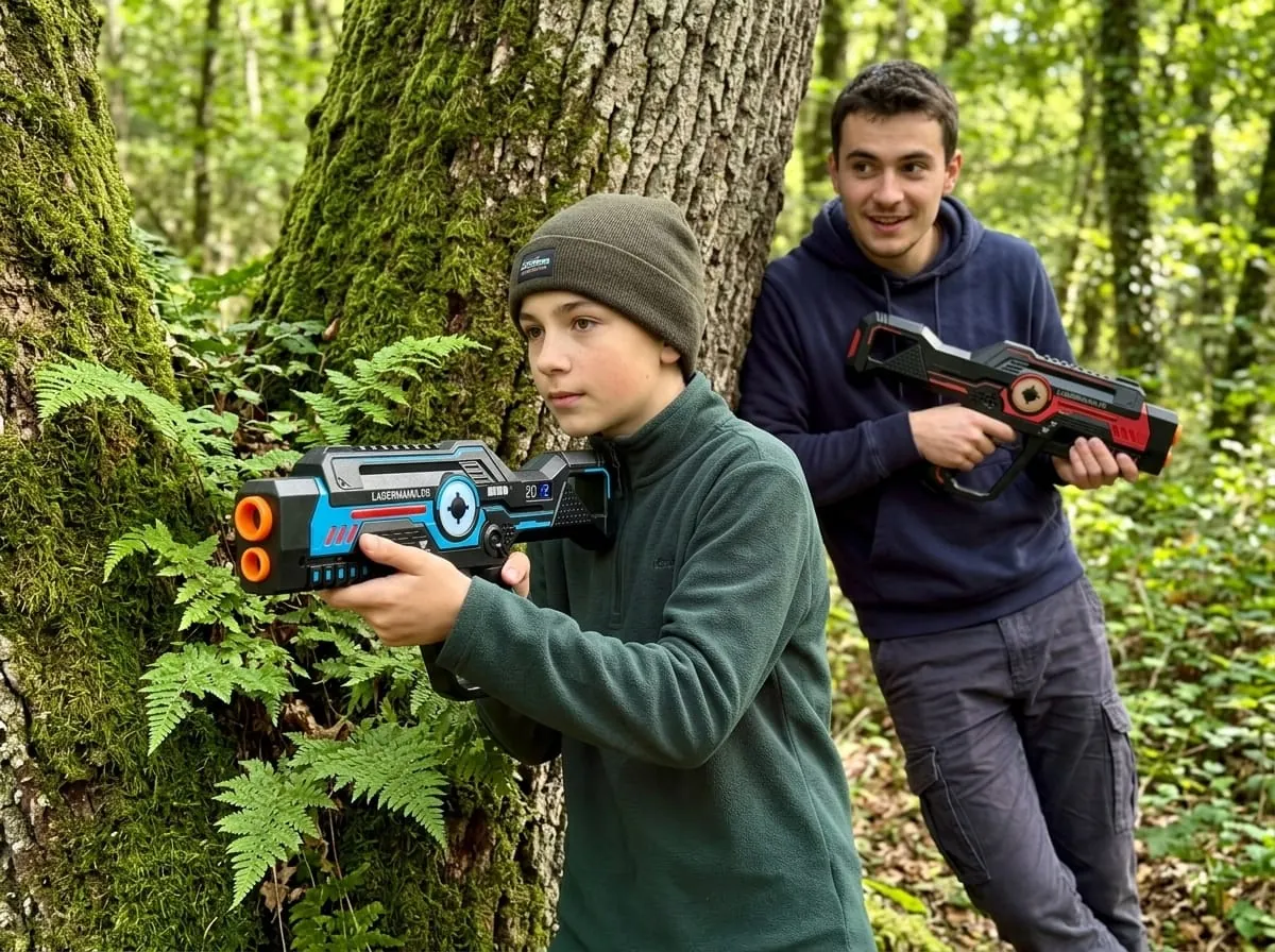 Joueurs de laser game en forêt équipés du pistolet anti-triche Lasermania derrière un arbre moussu